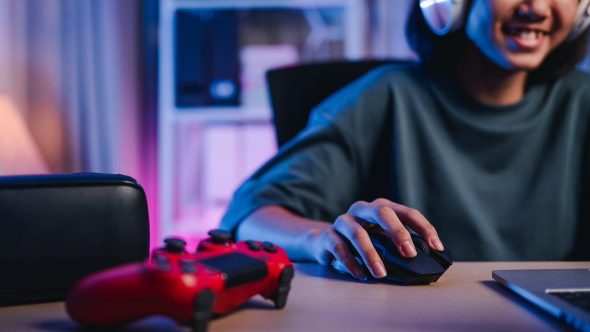 teen at desk, interacting with a computer and video game controller on desk