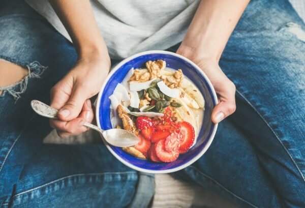 Granola and fruit bowl in hand for health eating habits.