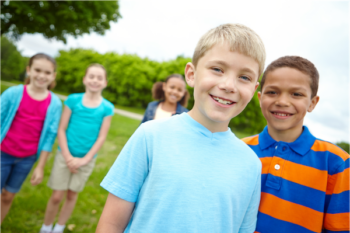 Multiple children outside and smiling.